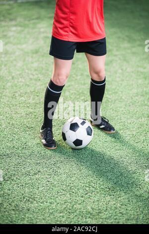 Soccer Ball zwischen den Beinen der aktiven Mädchen im Sport einheitliche stehen auf grün Fußballplatz während des Trainings Stockfoto