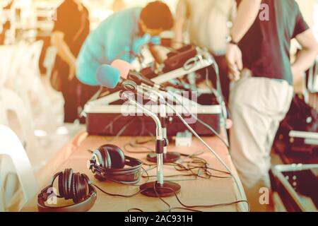 Zwei Mikrofone mit blauen und roten Schwämmen auf Stativ mit Kopfhörer auf den Tisch gelegt mit blur Bild der audio Techniker war die Installation und tes Stockfoto