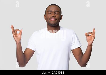 Ruhige friedliche African American man meditieren, eingedenk junge männliche Yoga mit geschlossenen Augen, Gefühl, Zen, kein stress Konzept, entspannend, romantisch Stockfoto