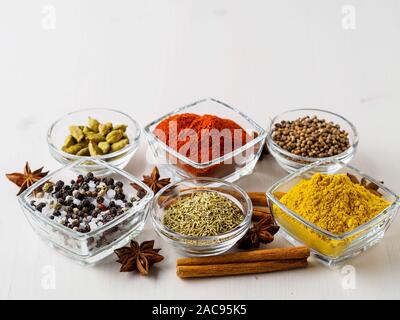 Gewürz set - Koriander, Paprika, Curcuma, Zimt, Sternanis, Rosmarin verschiedene Gewürze im Glas Tassen, auf weissem Holztisch, Seitenansicht, leere sp Stockfoto