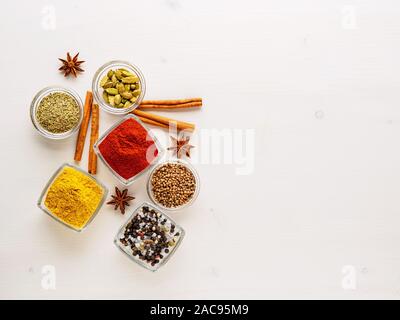 Gewürz set - Koriander, Paprika, Curcuma, Zimt, Sternanis, Rosmarin verschiedene Gewürze im Glas Tassen, auf weißem Holz- Tabelle, Ansicht von oben, leere Spa Stockfoto