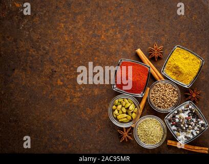 Orientalische Gewürz set - Koriander, Paprika, Curcuma, Zimt, Sternanis, verschiedene Gewürze im Glas Tassen, auf braun dunkel rostiges Metall Tisch, oben vi. Stockfoto