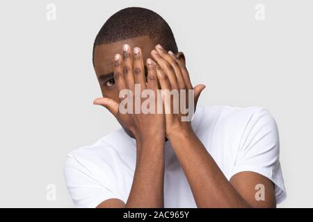 Unglücklich African American man versteckt sich hinter Hände erschrocken, verängstigten Jungen männlichen an Kamera suchen, Gefühl, Angst, Stress, negative Emotionen, Horror mov Stockfoto