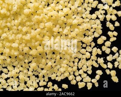 Raw trockene Körner couscous auf schwarzem Hintergrund, Nahaufnahme, Ansicht von oben Stockfoto