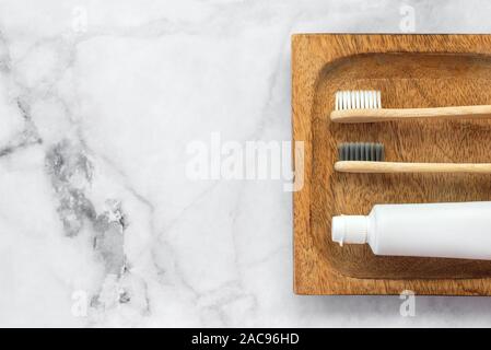 Der umweltfreundliche Zahnbürsten und Zahnpasta auf Stand aus Holz und Marmor. Zahnmedizinische und medizinische Konzept. Ansicht von oben, flach. Kostenloses Exemplar sp Stockfoto