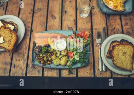 Overhead shot, eine Platte mit Räucherlachs und Salat und Brot auf einem Cafe Tabelle Stockfoto