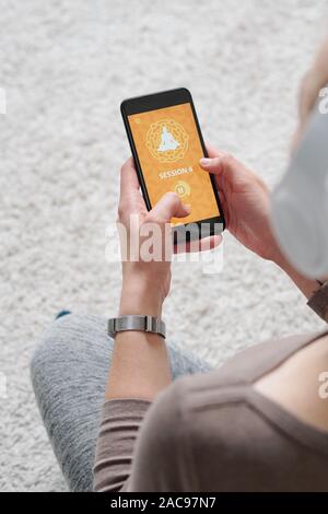 Die Hände der jungen aktiven, weiblichen Holding Smartphone während der Audiowiedergabe Stockfoto