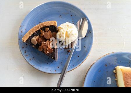 Overhead flatlay Blick auf ein Stück Schokolade Pekannusstorte mit Vanilleeis und ein Löffel auf einem blauen Platte Stockfoto
