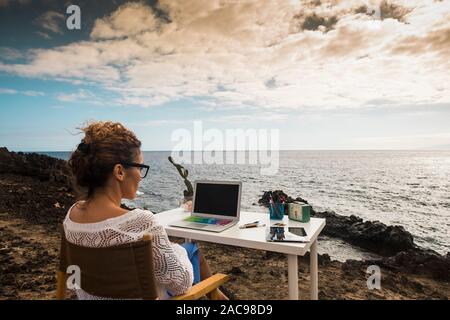 Moderne und alternative lifestyle Office wokstation mit kostenlosen Business Frau bei der Arbeit in Open Office mit herrlichem Blick auf das Meer - Freiheit von der üblichen Job-d Stockfoto
