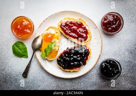 Sandwich mit verschiedenen süßen Konfitüren und Hüttenkäse auf hellen Hintergrund, Ansicht von oben mit der Kopie Raum Stockfoto