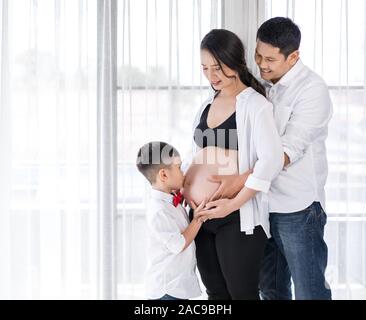 Happy Family Konzept, schwangere Mutter, Vater und Sohn küssen Stockfoto
