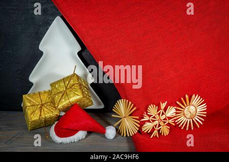 Festliche rot Weihnachten noch Leben mit Geschenken, handgefertigte Stroh Schneeflocken, weiß Xmas Tree und Santa hat über bunten hellen roten Stoff zu feiern. Stockfoto