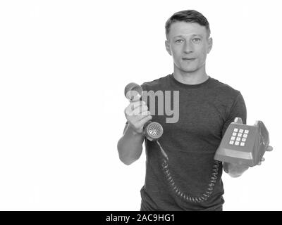 Studio shot der Jungen stattlichen kaukasischen Mann, der alten roten Telefon vor weißem Hintergrund Stockfoto