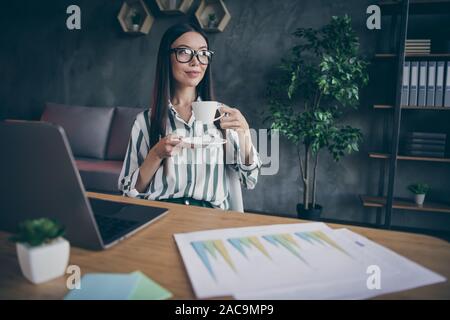 Foto fröhliche, positive Frau mit Tasse Tee trinken köstliche Getränk während der Pause bei der Arbeit als Finanzier Stockfoto