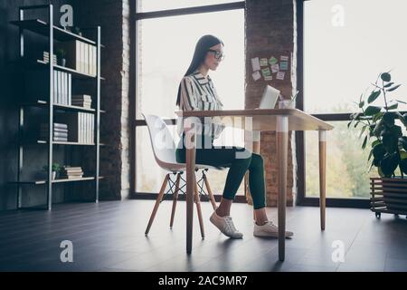 Volle Länge Körper Größe tief unter dem Blickwinkel - Foto von Intelligenten concetrated Mädchen arbeiten an Start-up vor dem Laptop im Licht, das durch das Fenster Stockfoto