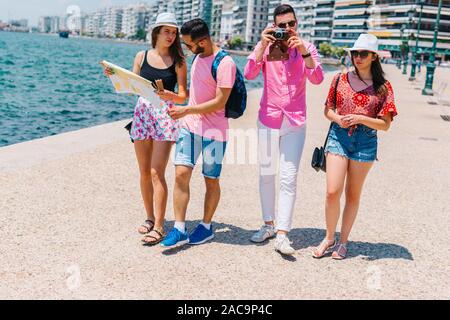 Ein paar ist das Lesen einer Karte, während die anderen Fotos ist, die ihren Sommer Urlaub. Stockfoto