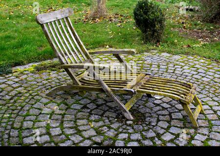Liegestuhl wit Patina, Flechten und Moos auf einem Kreis aus Steinen Stockfoto