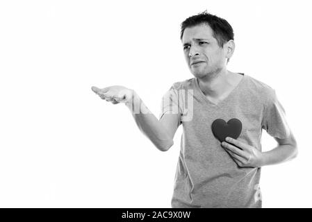 Studio shot der traurige junge Mann die Hand geben mit roten Herzen auf der Brust für den Valentinstag bereit Stockfoto