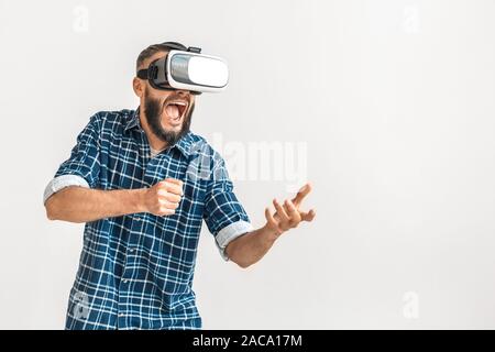 Reife bärtige Mann auf grauem Hintergrund mit Kopie Raum isoliert. Männlichen Erwachsenen in 3-D-Brille auf dem Kopf schreien, spielen Spiele Stockfoto