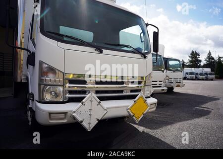 Kleine kompakte Kabine über kommerziellen Semi Trucks mit Box Anhänger für industrielle Cargo stehen in Reihe auf Lager Parkplatz tragen, wartet auf die nächste l Stockfoto