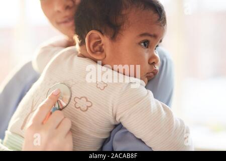 Nahaufnahme der Mutter mit Baby auf ihre Hände mit dem Arzt Hören auf sein Herzschlag mit Stethoskop Stockfoto