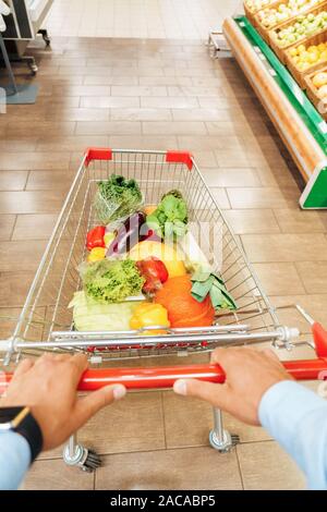 Die täglichen Einkäufe. Junge Frau im Supermarkt mit Karre voller Gemüse - Ansicht von oben Stockfoto