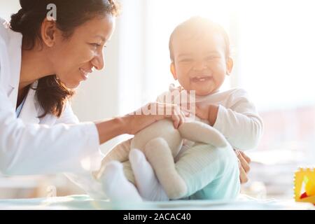 Lächelnd Krankenschwester Spaß zusammen mit Kind sie mit Spielzeug spielen während Ihres Besuchs Stockfoto