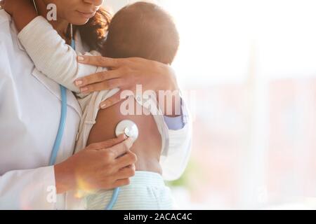 Arzt Holding Baby und auf Ihn zu hören mit Stethoskop Stockfoto