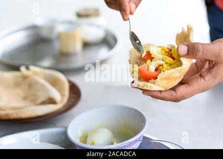 1001 männliche Frühstücken zu Hause. Einfach und lecker Essen. Frisches Fladenbrot gefüllt mit Ei und Tomaten-, Gewürz- und Olivenöl. Stockfoto