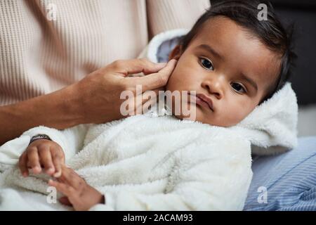 Close-up von niedlichen Baby Boy liegen auf den Händen seiner Mutter, während sie streichelte seinen Kopf und bettete Ihn Stockfoto