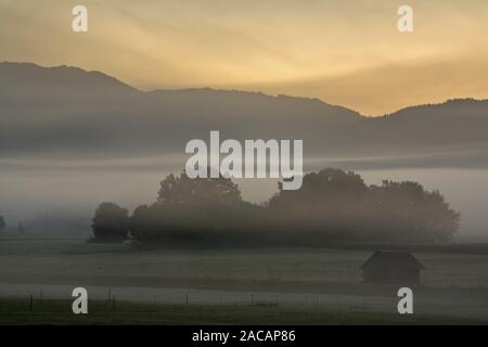 Neblige Landschaft mit Hütten in den Bayerischen Voralpen, Deutschland Stockfoto