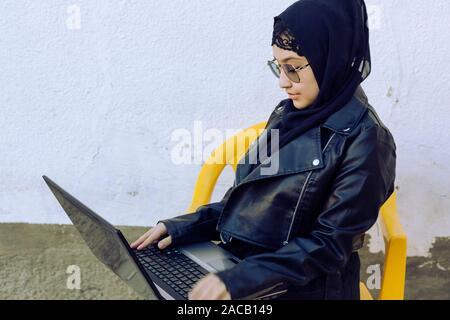 Schönen Nahen Osten arbeiten mit dem Laptop. Cute arabischen muslimischen Frau im hijab mit Laptop im Freien posieren. Blogger, Vlogger, Freelancer Mädchen an Stockfoto