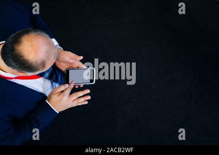 Luftaufnahme von einem Mann mit einem Mobiltelefon auf schwarzem Boden Stockfoto
