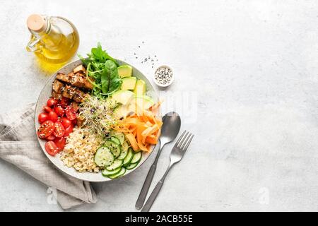 Vegetarisch Vegan Salatschüssel oder Buddha Schüssel mit Getreide, Tofu, Avocado, Gemüse und Grüns. Mahlzeit auf grauem Beton Hintergrund ausgeglichen. Ansicht von oben, cop Stockfoto