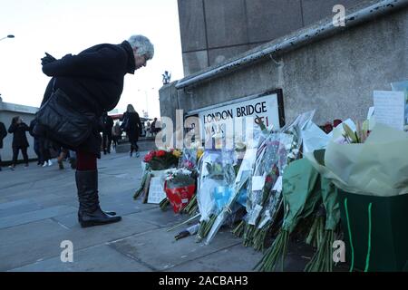 Ein Passant hält an Blumen im London Bridge in London links zu schauen, nach dem Terroranschlag am Freitag. Eine Mahnwache am Montag statt, Gedenken an die Opfer des Angriffs zu zahlen und die Notdienste und Mitglieder der Öffentlichkeit, die auf den Vorfall reagiert zu ehren. Stockfoto