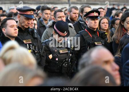 Polizisten an einer Mahnwache in Guildhall Yard, London, die Opfer aus der London Bridge Terroranschlag zu Ehren, wie auch die Mitglieder der Öffentlichkeit und der Rettungsdienste, die ihr Leben riskierten, um anderen zu helfen, nach einer terroristischen trägt eine gefälschte Selbstmord Weste auf des Messers rampage tötet zwei Menschen gingen, wurde von der Polizei am Freitag erschossen. Stockfoto