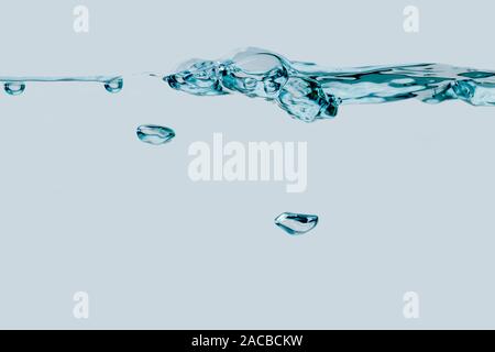 Studio geschossen von einer Reihe von Blasen an der Wasseroberfläche mit zwei einzelnen aufsteigende Luft- Blasen in der Seitenansicht vor hellen blauen Hintergrund. Stockfoto