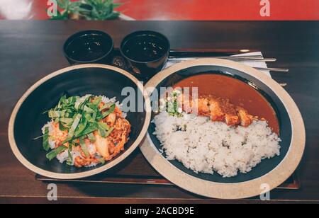 Zwei Portionen koreanisches Essen: Schüssel und rühren fryed Fleisch und Kimchi und Platte von Curry Reis mit tonkatsu Schnitzel Stockfoto