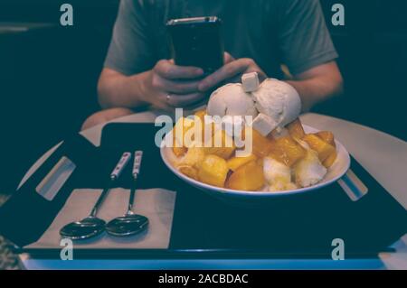 Der Mensch ist unter Foto von Mango bingsoo - Koreanische rasiert Eis Dessert mit süßen Toppings Stockfoto