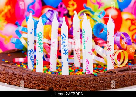 Chocolate Brownie Geburtstag Kuchen mit Streuseln und hat acht unbeleuchteten Happy Birthday Kerzen mit den Worten bedruckt. Stockfoto