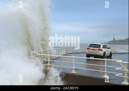 Aberystwyth Ceredigion Wales/Großbritannien, 28. November 2019: Jeep Fahrzeug an der Küste, mit hohen Wellen Bremsen über das Meer Verteidigung Wand geparkt. Stockfoto