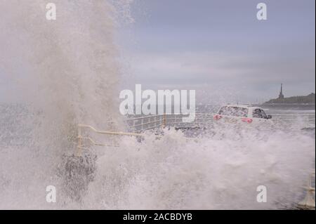 Aberystwyth Ceredigion Wales/Großbritannien, 28. November 2019: Jeep Fahrzeug an der Küste, mit hohen Wellen Bremsen über das Meer Verteidigung Wand geparkt. Stockfoto