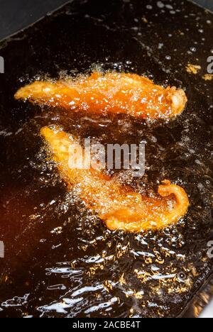 Fischkochen in einer Fritteuse in einem Fisch- und Spangeschäft in Großbritannien Stockfoto