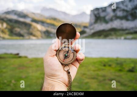 Eine Hand hält einen Kompass in einem Berg- und Seenlandschaft Stockfoto