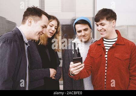 Junger Mann mit etwas Lustiges auf seinem Smartphone an eine Gruppe von Freunden - Städtische jugendliche Spaß haben und gemeinsam lachen Stockfoto