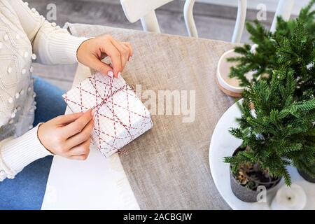 Der Frau die Hände gebunden Weihnachtsgeschenk am Tisch. Wenig Tannen am Küchentisch. Stockfoto