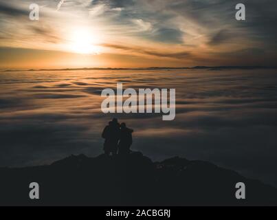 Paar Wanderer Erfolg bei Sonnenuntergang in den Bergen. Mann und Frau auf Rocky Mountain mit Blick auf den wunderschönen Sonnenuntergang inspirational Querformat Stockfoto