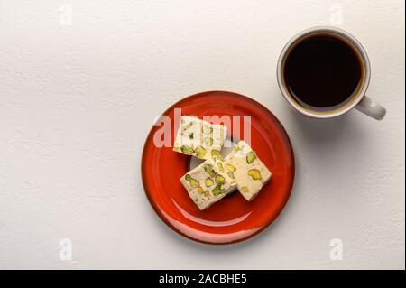 Nougat auf einen Teller und eine Tasse Tee auf hellen Hintergrund Stockfoto