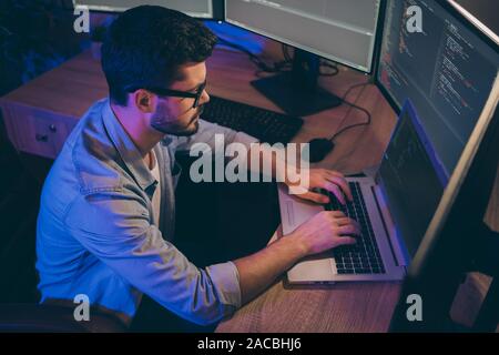 Profil Foto von IT-Spezialist Kerl Spät in der Nacht sitzen bequemen Bürostuhl, Hände auf der Tastatur suchen Monitore arbeiten website Debugging Stockfoto