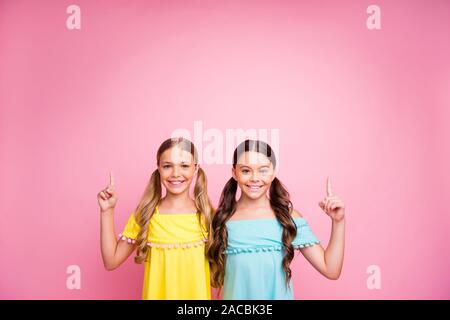 Foto von zwei wunderschöne, kleine Damen die besten Freunde, die Finger nach oben, leeren Raum Beratung neue niedrige Verkaufspreise blau gelb Kleider isoliert tragen rosa Stockfoto